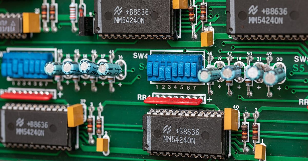 A close-up of a green circuit board with chips and components