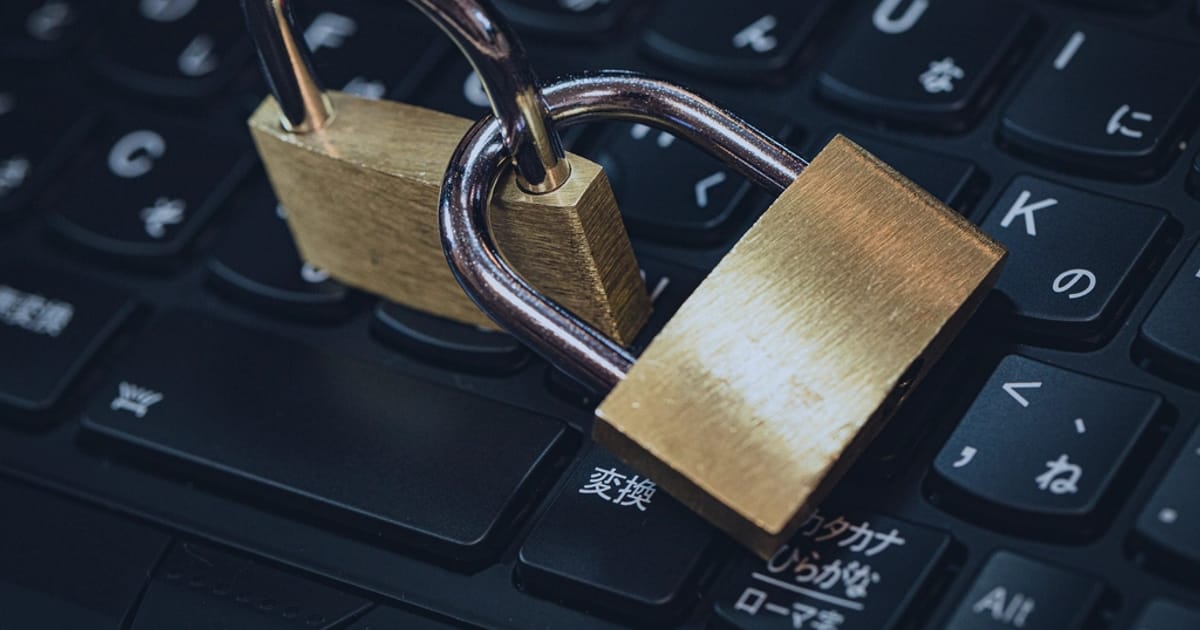 Two brass padlocks interlocked on a laptop keyboard